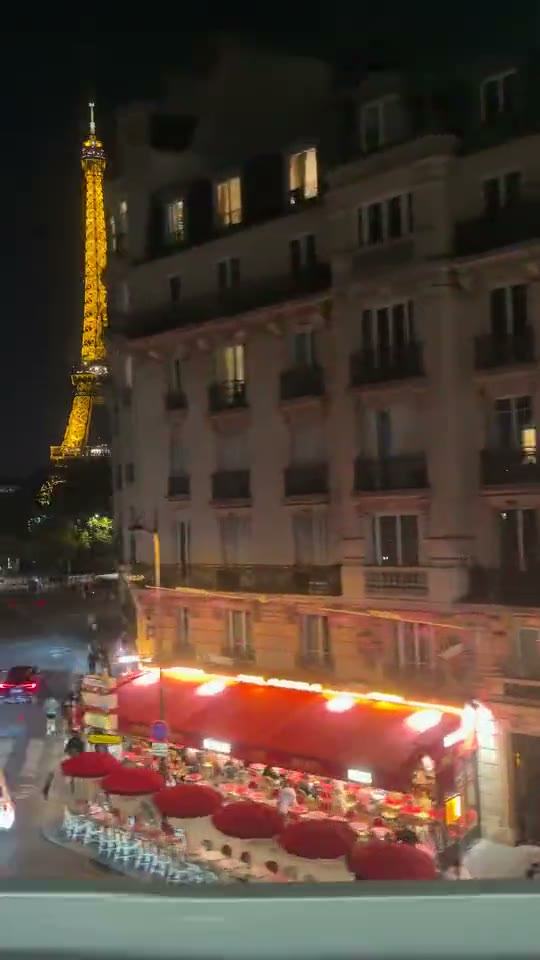 Vista de la calle, edificios y restaurantes con una parte de la Torre Eiffel