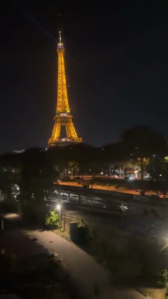 La Torre Eiffel iluminada completa y el río en la parte inferior del encuadre